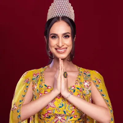 A celebratory portrait of Tamanna Bharat, winner of Miss Asia Global 2024. This clean, studio shot with her crown and a grateful 'namaste' pose is perfect for official announcements and press kits.