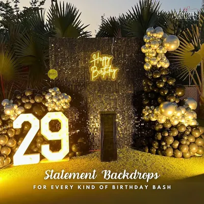 A statement backdrop for a 29th birthday bash. This outdoor setup features a bold black and gold balloon arrangement against a shimmering sequin wall, complete with marquee numbers to mark the special year.
