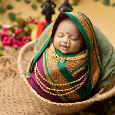 Our 'Chotishi Rakhumai' newborn, wrapped in a traditional Paithani-style saree and adorned with delicate jewelry, sleeping peacefully in a basket.