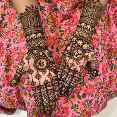 This design beautifully incorporates the couple's initials, "AS" and "CD," into circular frames on the palms. The surrounding patterns include elephants and lotuses for a traditional touch.
