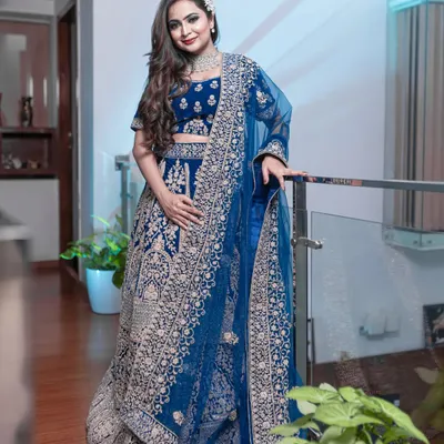 This peacock blue velvet lehenga is pure royalty. The heavy silver and pink embroidery makes it a perfect choice for a bride's reception or a grand wedding event.