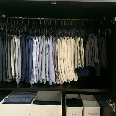 A clean and efficient system for a man's wardrobe. Trousers are hung on uniform hangers, while labeled bins below store jeans, socks, and handkerchiefs. This is organization that performs.
