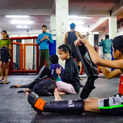 These kids are not weak. They are learning to face challenges head-on. Here, they are getting ready for their kickboxing drills, putting on their shin guards and preparing for practice.