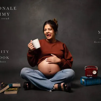 A fun and modern take on maternity photography. This mom-to-be shows off her playful personality and bare bump in a casual outfit, surrounded by books and a retro radio for a personalized touch.