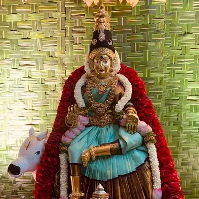 A close-up of a Varamahalakshmi deity we prepared for a home pooja. The goddess is adorned with a beautiful saree and garlands, seated against our signature woven coconut leaf backdrop for a truly divine setup.