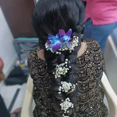 An intricate fishtail braid adorned with fresh baby's breath and vibrant purple orchids. This is a stunning and unique hairstyle for a Mehendi or Sangeet ceremony.