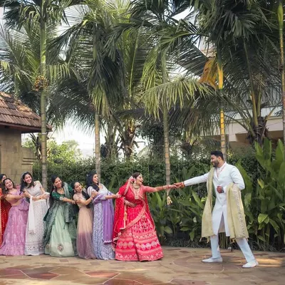 A playful tug-of-war between the groom and the bridesmaids, who are all trying to pull the bride away. A classic, fun-filled wedding moment.