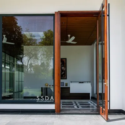 The entrance to The Green Axis, a commercial office I designed. The large pivot door and floor-to-ceiling glass immediately connect the interior reception area to the green landscape outside, setting a tone of openness and tranquility.