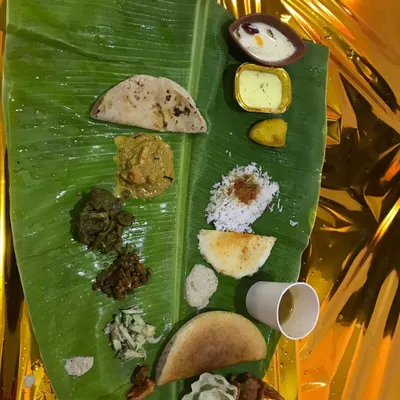 A complete South Indian meal served on a banana leaf. This spread includes everything from rice and roti to multiple vegetable curries (palyas), sambar, rasam, and a traditional sweet. I ensure every item is authentic and tastes just like home-cooked food.