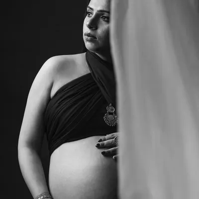 A quiet moment of reflection. This monochrome portrait uses soft light to highlight the beautiful curve of the baby bump and the mother's thoughtful expression.