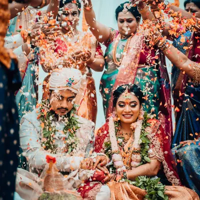 A beautiful, wide-angle shot of a South Indian wedding ritual, capturing the couple surrounded by the joyous blessings of their family and friends.