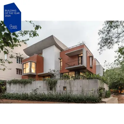 An exterior view of the Nairy Residence, which was nominated for the ArchDaily 2024 Building of the Year award. The composition balances heavy, protective forms with open, cantilevered balconies, expressing the home's layered approach to privacy and openness.