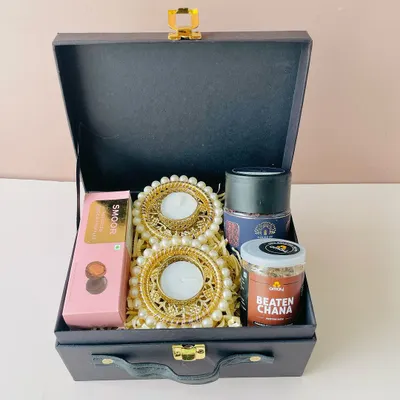 This stylish black suitcase box is a versatile option for corporate gifting. Here, it's curated with pearl-decorated diyas, gourmet snacks, and chocolates for a complete festive feel.