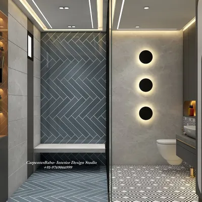 A modern bathroom with a bold, geometric-patterned floor and a dark blue herringbone tile in the shower area. The wall-mounted toilet and backlit circular lights add a contemporary, high-end feel.