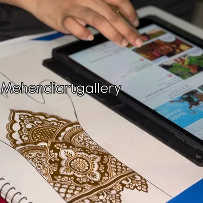 My teaching setup often includes both traditional practice on paper and digital resources. Here you can see me referencing designs on a tablet while practicing a bridal pattern, a modern approach to learning mehendi.