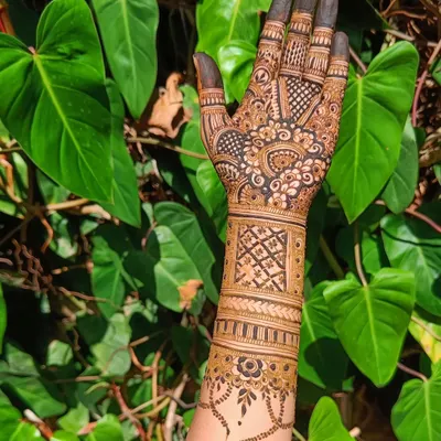 A beautiful design featuring a mix of geometric bands and a delicate vine pattern on the wrist, shot against a lush green background.