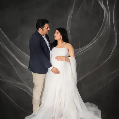 An angelic portrait for a glowing mother-to-be. The flowing white gown and ethereal fabric toss create a sense of grace and beauty, making for a timeless maternity photograph.