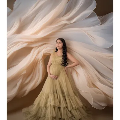 A dramatic shot featuring a mom-to-be in a golden-hued ruffled gown with fabric artfully arranged to create a fan-like effect. This showcases our creative styling options.