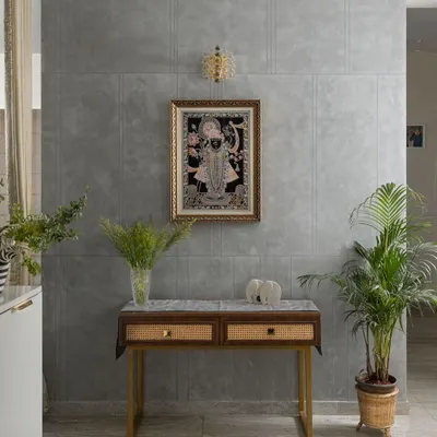 A serene corner dedicated to spirituality. I designed this space with a simple console table featuring cane-fronted drawers, set against a calm, grey textured wall. The traditional artwork and brass lamp complete the tranquil atmosphere.