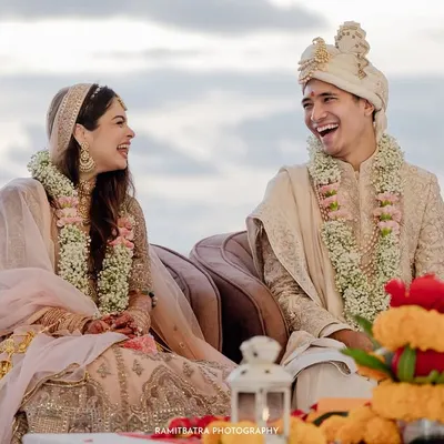 A moment of shared laughter between the bride and groom during their sunset pheras on a beach in Thailand.