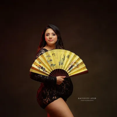 A stunning and unique portrait using a traditional fan as a prop. The red lighting and lace bodysuit create a bold and artistic look.