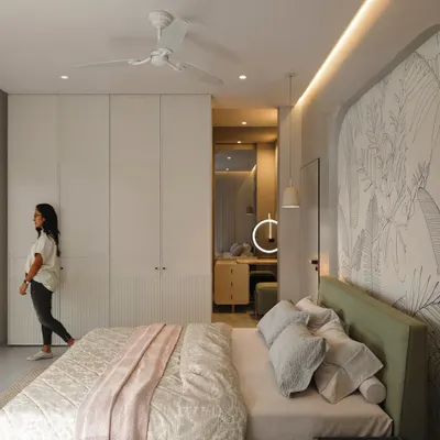 A bright and airy bedroom with a custom arched headboard featuring a line-art mural. The room includes a walk-in wardrobe and a dedicated vanity area.