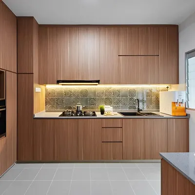 This kitchen features floor-to-ceiling wood laminate cabinets, creating a warm and cohesive look. We installed under-cabinet lighting to illuminate the patterned tile backsplash and countertop, adding visual interest and task lighting. The integrated oven and black appliances provide a modern contrast to the natural wood finish.