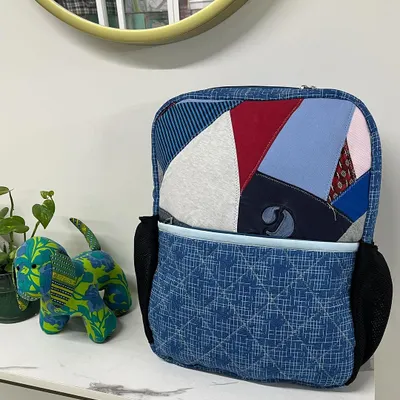 A custom-made backpack created by upcycling a client's old T-shirts and shirts. This unique bag includes a laptop compartment and inner pockets, making it both personal and practical.