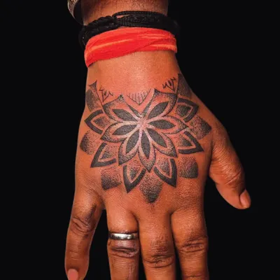 A bold geometric mandala on the hand, featuring clean lines and dot work shading. This style is excellent for covering old tattoos with a balanced and intricate design.