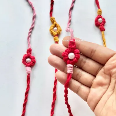 Holding one of my handmade floral Rakhis. I designed these for Rakshabandhan, featuring a delicate flower knot with a pearl bead in the center and twisted ties.