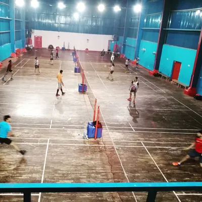 An elevated view of our badminton hall filled with players during a busy evening session. The image captures the scale of our operations and the dedication of our athletes.