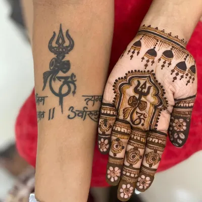 For the devotee, a design that keeps Mahadev close. This special mehendi incorporates the Trishul and Om symbols, designed to sit alongside the client's existing tattoo, creating a powerful and personal statement of faith.