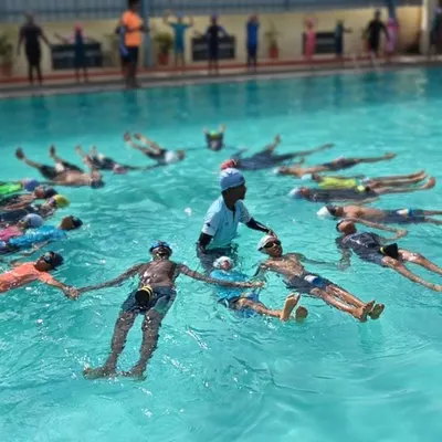 Our instructor guides the class through various poses during an International Yoga Day event. The group holds hands, creating a circle of shared energy and focus in the water.