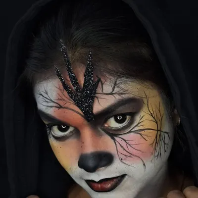 The full gothic fantasy look, complete with a dark hood to frame the face. The makeup features a central glitter applique on the forehead and fine, hand-drawn branches spreading across the face.
