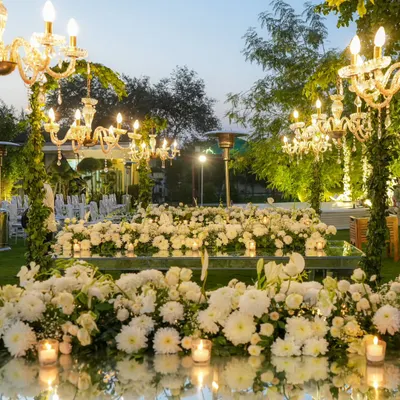A breathtaking scene from a 25th-anniversary dinner. Mirrored tables are covered in a sea of white chrysanthemums and candles, reflecting the warm glow of crystal chandeliers above.
