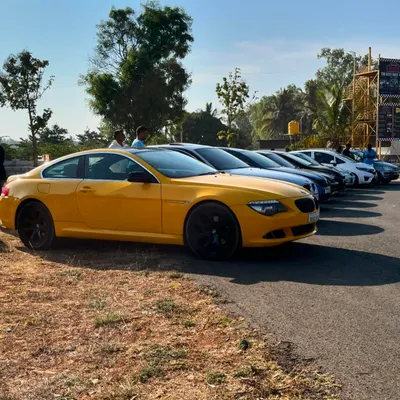 A lineup of high-performance cars, including a bright yellow BMW, at a Cars & Coffee meet. This is the kind of quality and passion you'll find at our community events.