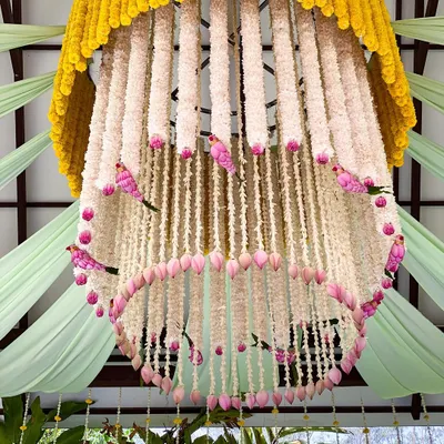 A magnificent floral chandelier, crafted from marigolds, tuberoses, lotus buds, and whimsical pink birds. This is a true statement piece, adding a touch of magic to the wedding decor.