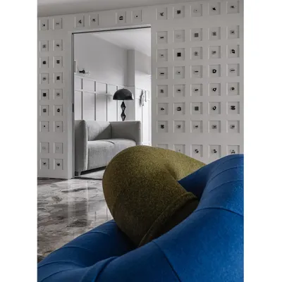 Welcome to Frenchie Haus. The living room immediately greets you with bold color choices, like the vibrant blue and green 'Loops' sofa, and the unique Morse code wall in the background.