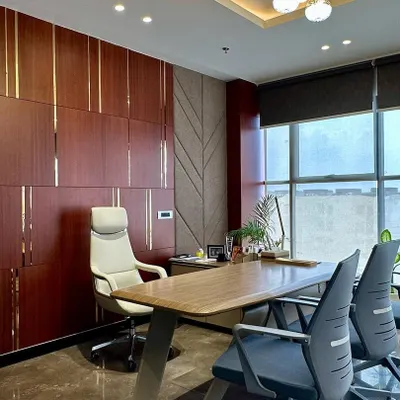 This MD room combines rich mahogany-toned wood panels with textured fabric sections and fine metallic strips. The ergonomic executive chair and spacious desk are positioned to take advantage of the natural light from the large window.