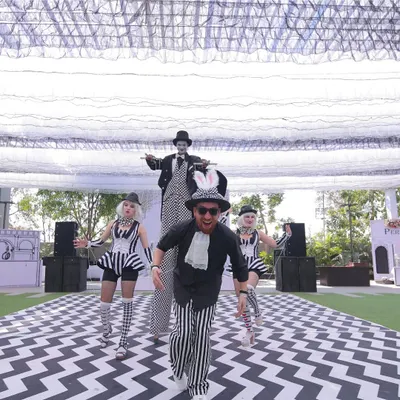 The energy of our 'Line Art Carnival' is captured in this shot. We hired and costumed performers, including a stilt walker, to match the black-and-white theme and interact with guests on a custom chevron-patterned walkway.
