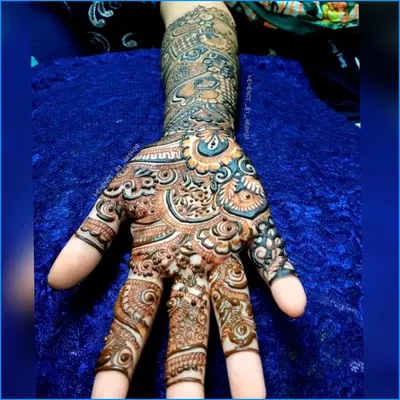 A close-up shot of a single palm, showcasing the incredible detail in the finger work and the central patterns. The use of light and dark shading adds depth to the design.