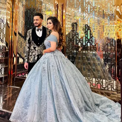 A happy client and her partner at their engagement. She is wearing my popular powder blue off-shoulder ball gown, which features delicate embroidery and a flowing train that looks stunning in photos.