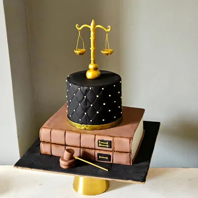 A cake for a lawyer, this design is both professional and artistic. It features two fondant-covered tiers designed to look like law books, topped with a quilted tier, an edible gavel, and the scales of justice.