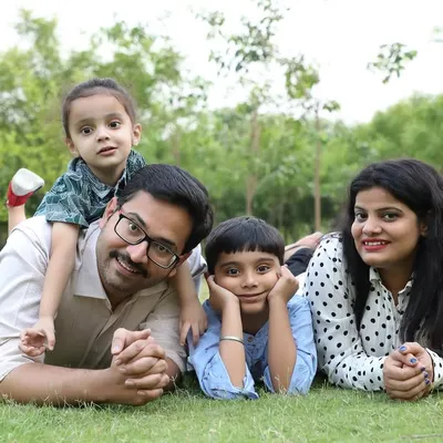 A happy family portrait taken during a relaxed outdoor photoshoot. Lying on the grass together creates a comfortable and intimate setting for a beautiful group picture.