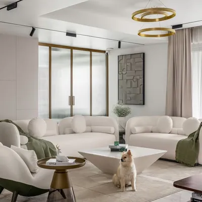 In this contemporary living room, we paired plush off-white sofas with dual-tone armchairs to create a cozy yet elegant seating arrangement. The space is grounded by a geometric coffee table and accented with touches of green and bronze, reflecting a harmonious and minimalist design.
