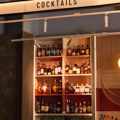 The view from behind our bar, fully stocked with a world-class selection of spirits. The 'Cocktails' sign says it all: this is where the magic happens. We can create a custom bar menu for your event.