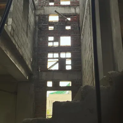 The central courtyard of a house under construction in Bangalore, viewed from the ground level. This image reveals the raw brick and concrete structure, with carefully planned openings that will soon flood the space with light.