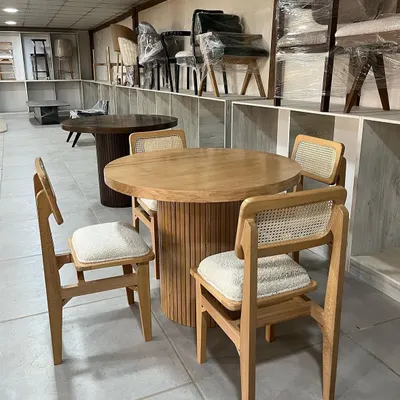 A beautiful four-seater dining set featuring a round table with a fluted base and matching chairs with cane backrests. This set is crafted from light-colored solid wood.