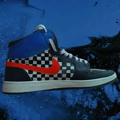 A side profile of a custom-painted high-top. I added a classic black-and-white checkerboard pattern and painted the swoosh a vibrant orange-red for a pop of color.