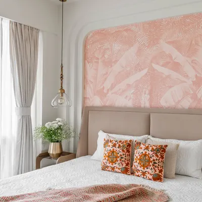 A tranquil bedroom from 'Project Lily,' featuring a custom bed with a beige upholstered headboard. The focal point is the arched niche with a delicate pink tropical wallpaper, creating a soft and dreamy ambiance.